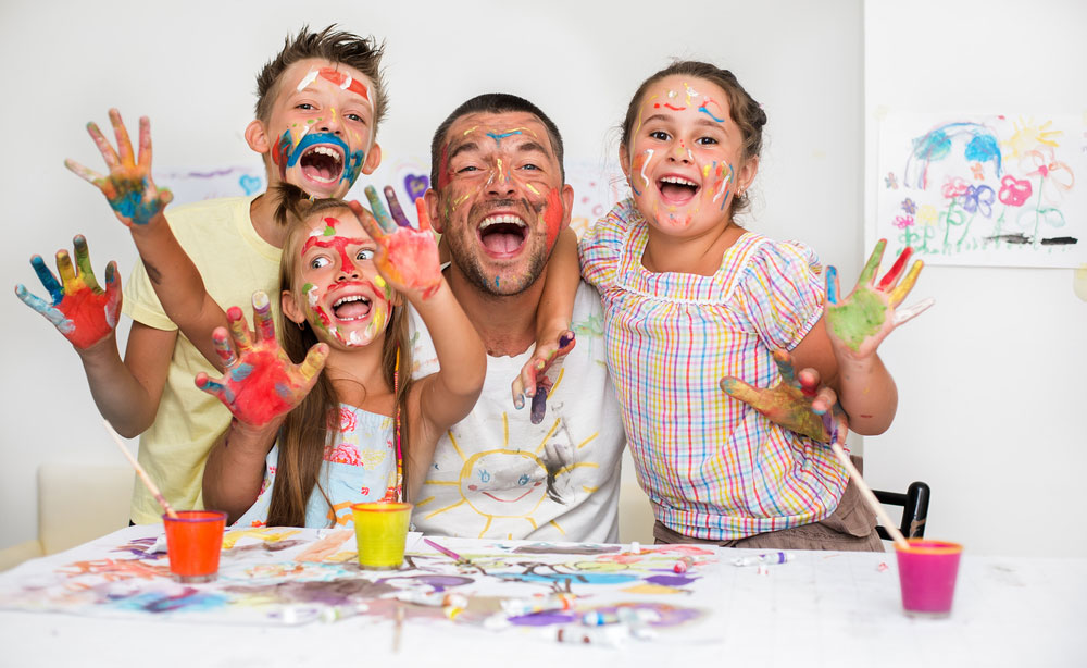 Portrait of a cute happy father with children painting and having fun